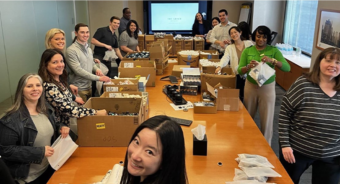 Employees adding supplies to boxes around a table. 