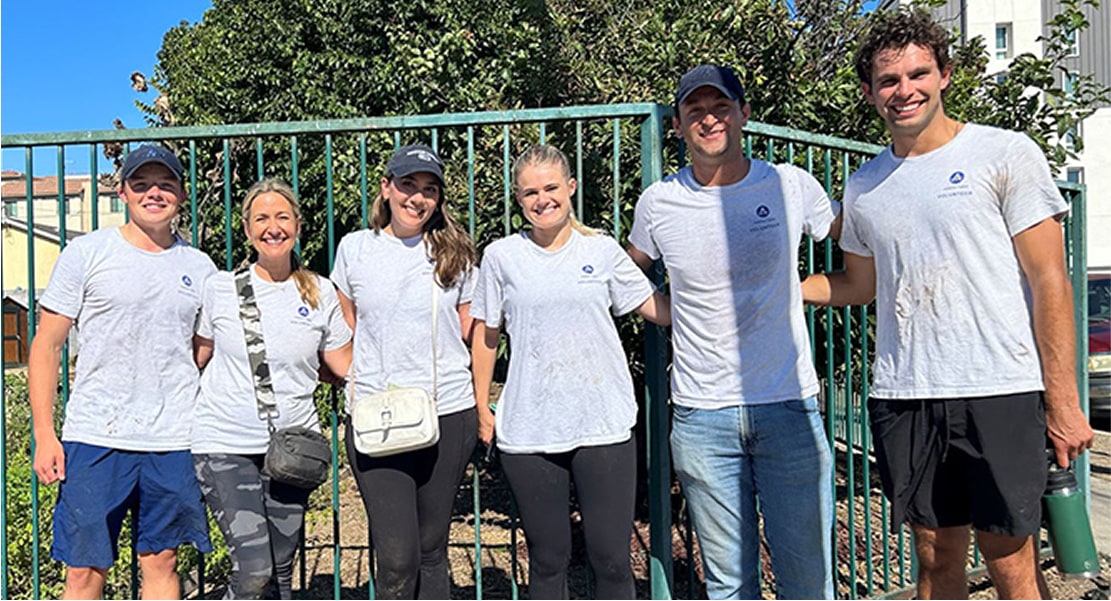 Employees standing outside taking a group photo with matching shirts.