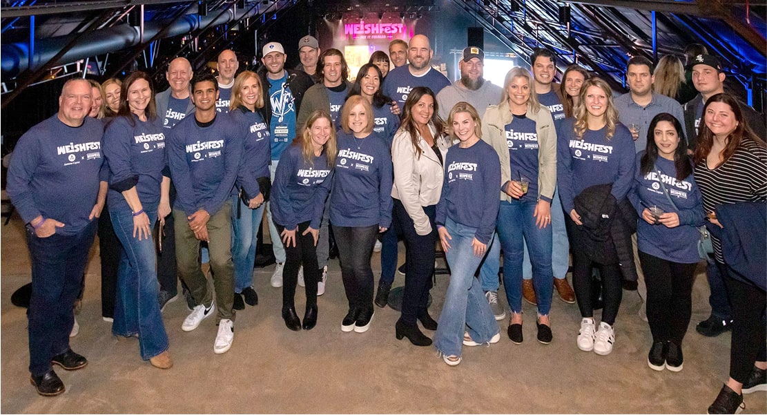 Employees at a concert taking a group photo with matching shirts.