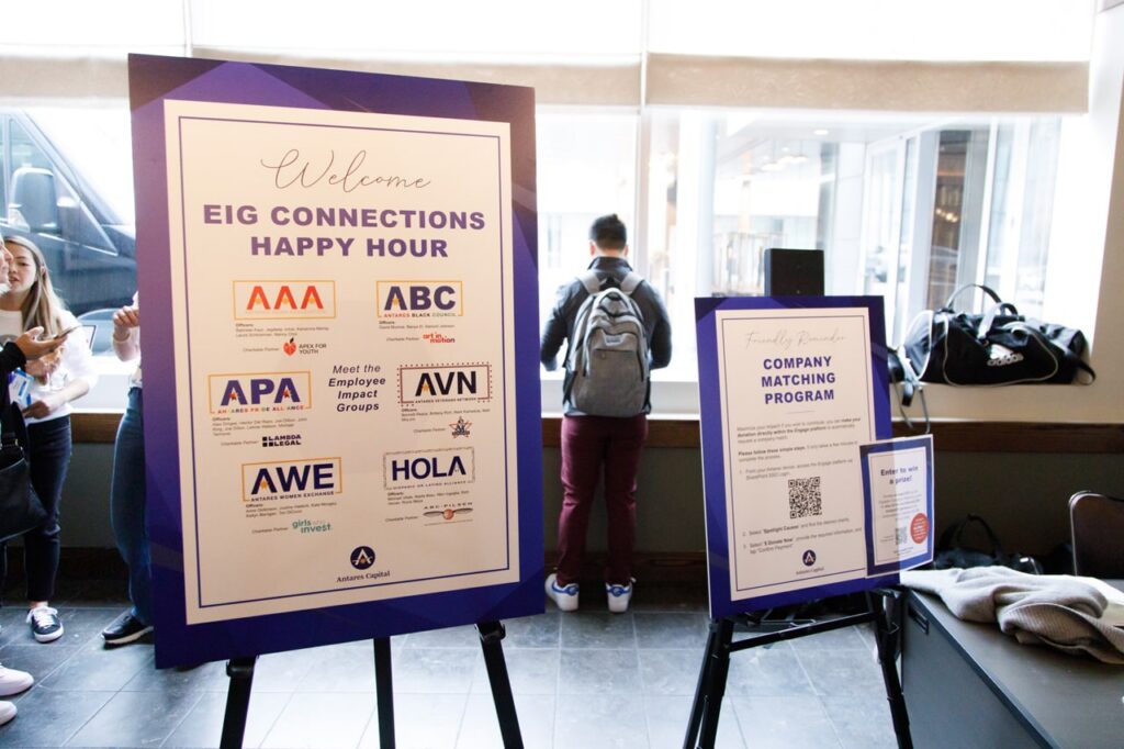 A sign that reads: “Welcome. EIG Connections Happy Hour” and features various company logos.