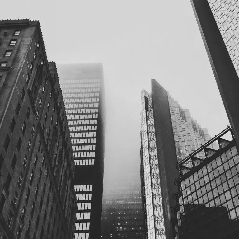 A black & white photograph of skyscrapers in a city scene.