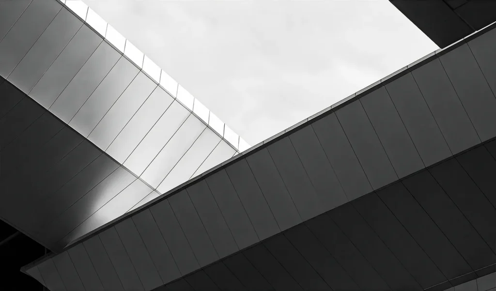 An abstract black and white photo of building a building against a clear sky.