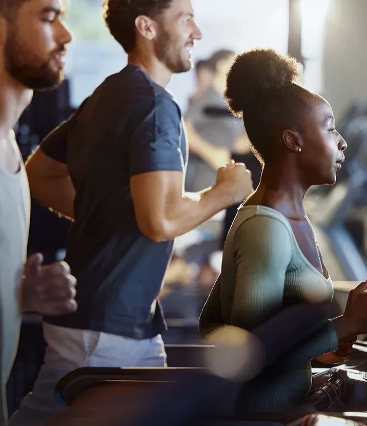 A photo of three people running on treadmills in a gym.