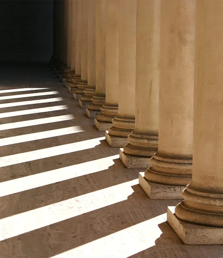 A dramatically shadowed photo of columns casting shadows on the ground.