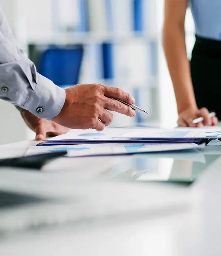 A photo of two people in business attire reviewing documents on a table.